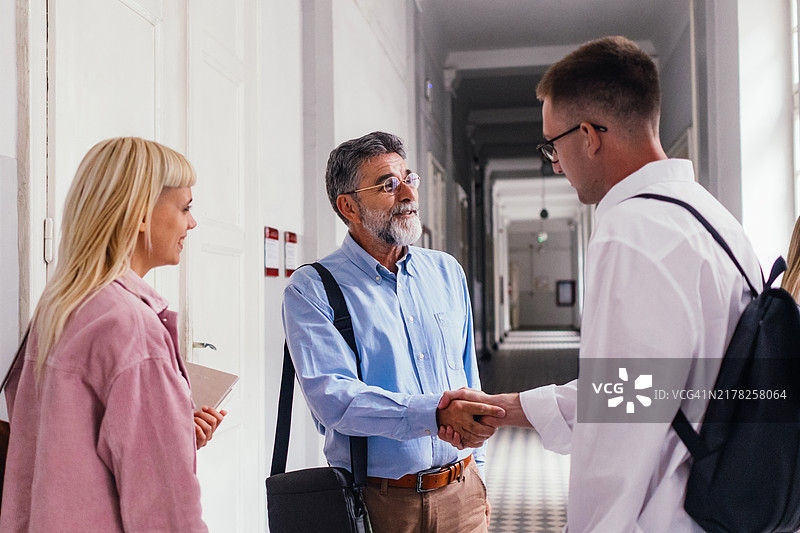 老师和学生在学校走廊友好握手图片素材