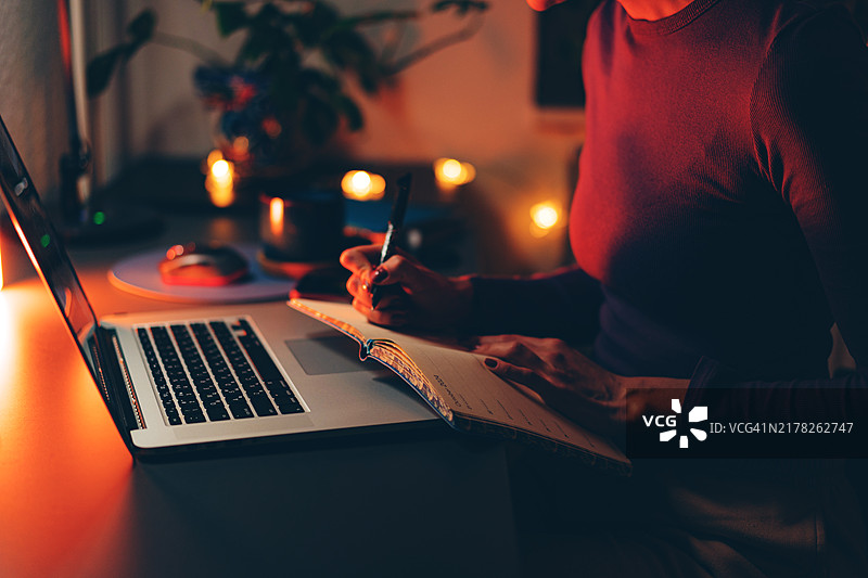 温馨的夜间工作空间 – 女人在烛光下写作图片素材