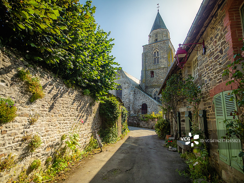 法国最美村庄之一圣苏里亚克村的街道景色，花岗岩房屋装饰着鲜花和攀缘植物，尽头是圣苏里亚克教堂图片素材