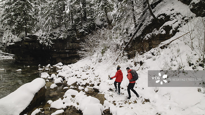 新鲜降雪中探索河岸的徒步旅行者航拍图片素材
