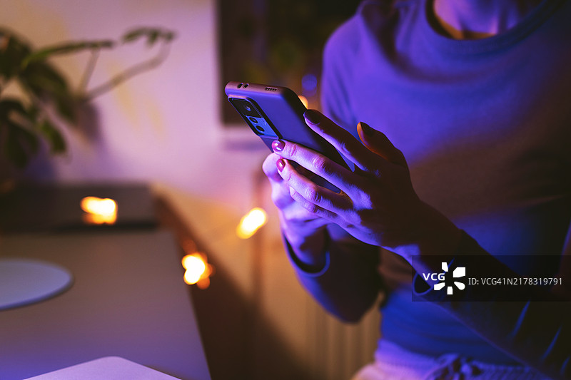 在家用智能手机浏览的夜晚——舒适的科技生活方式图片素材