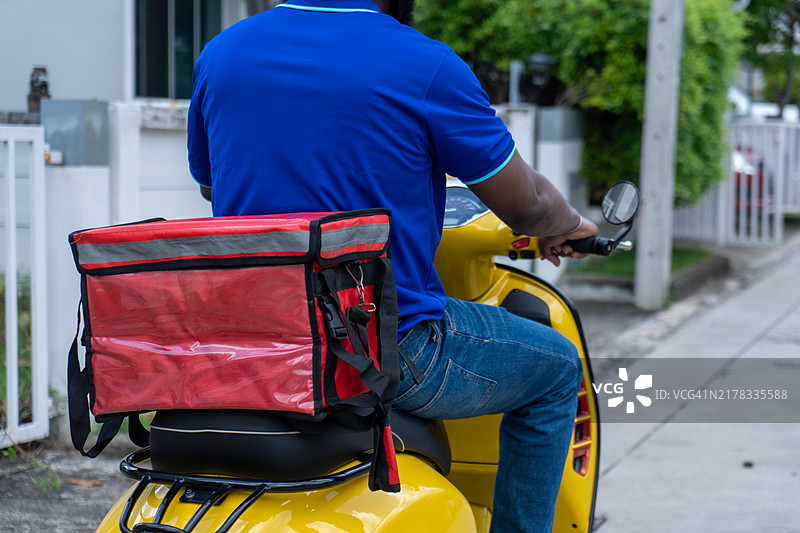 外卖员骑着后背带着红色大包的摩托车的背影图片素材