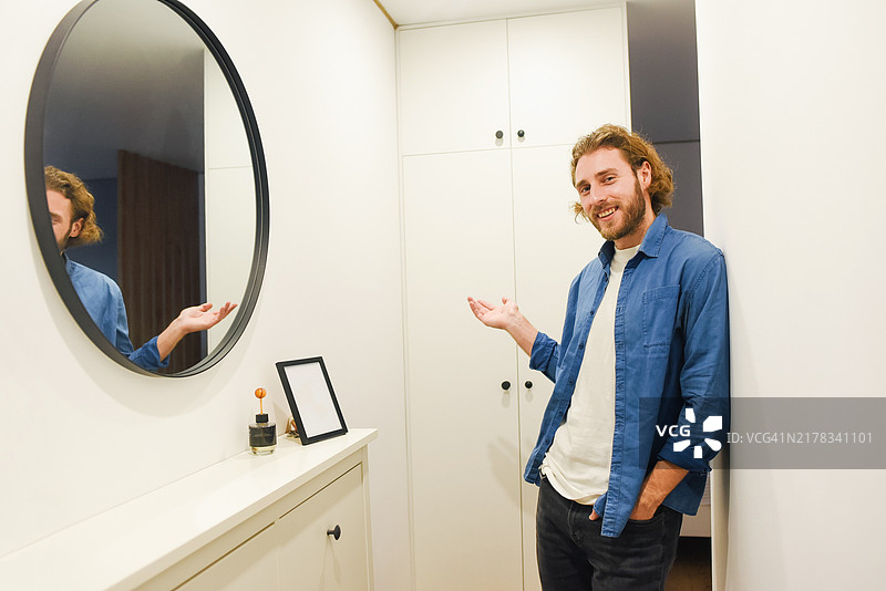 一位英俊的络腮胡男子站在明亮的房间里，身穿牛仔衬衫，外形俊美，留着长发，休闲风格。图片素材