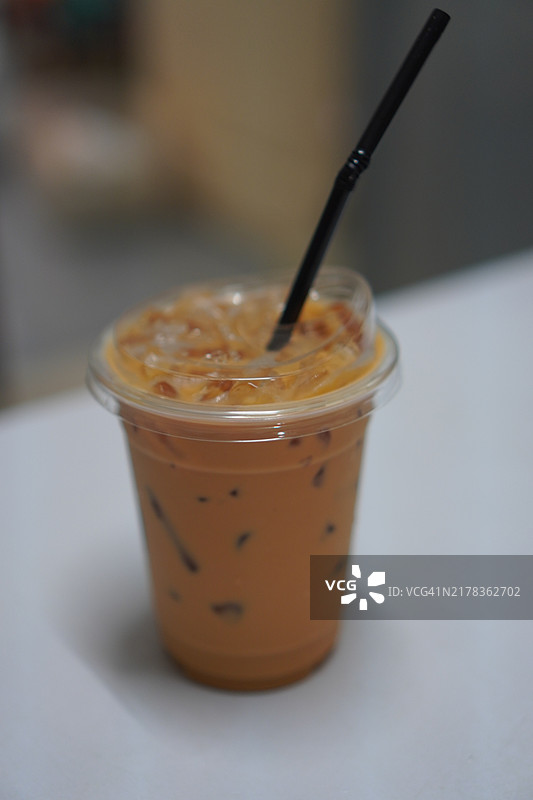 白色桌子上的塑料杯冰奶茶饮品图片素材