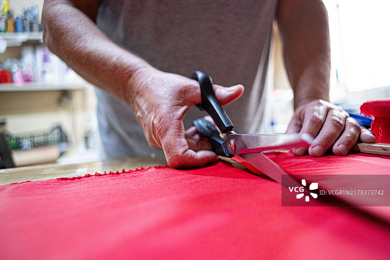 工匠用剪刀裁剪红色布料的特写镜头图片素材
