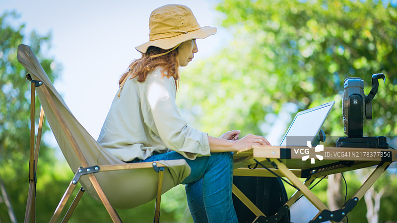 亚洲女性在夏季露营时使用笔记本电脑工作图片素材