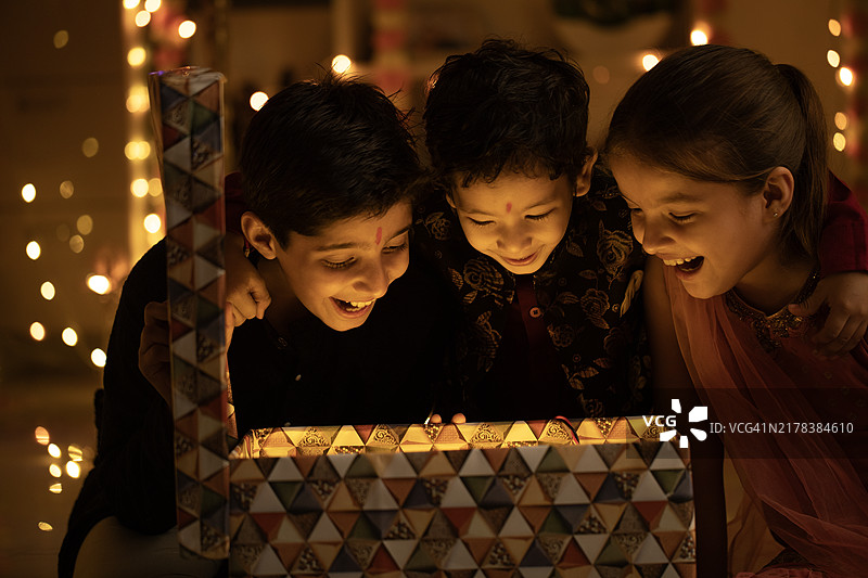 快乐的兄弟姐妹在家打开排灯节礼物图片素材