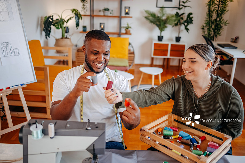 人们在家使用缝纫机并挑选线色来修理衣服图片素材