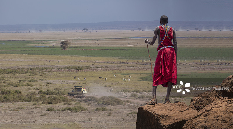 非洲：马赛牧羊人在萨瓦纳 watching 一辆汽车图片素材