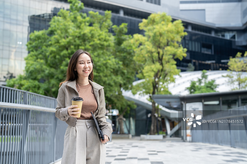 带着咖啡和平板电脑在户外行走的微笑女人图片素材