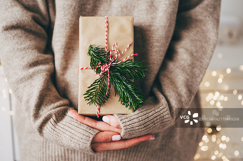 圣诞节包装创意，圣诞节包装工作区。用牛皮再生纸包裹礼品盒的女性双手。环保、可持续、零浪费、天然色的圣诞礼品盒在木制背景上。图片素材