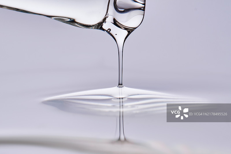 紫色背景上的滴管和精华液滴图片素材