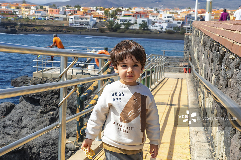 在海边享受暑假、在海边山坡上微笑的男孩图片素材