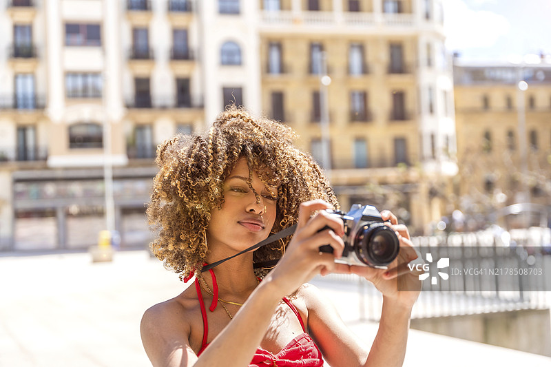 卷发黑发美女在夏季城市拍照图片素材