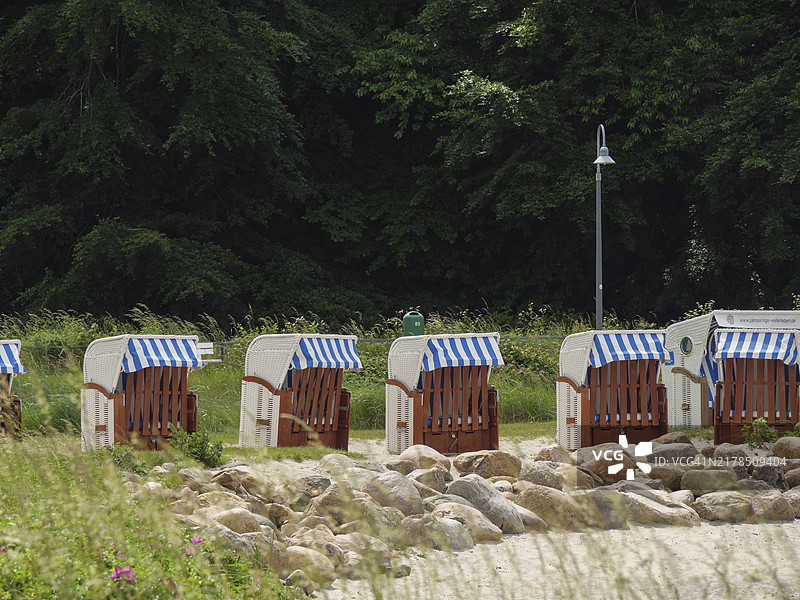 绿地上的多把沙滩椅，背景是树木和前景是石头图片素材