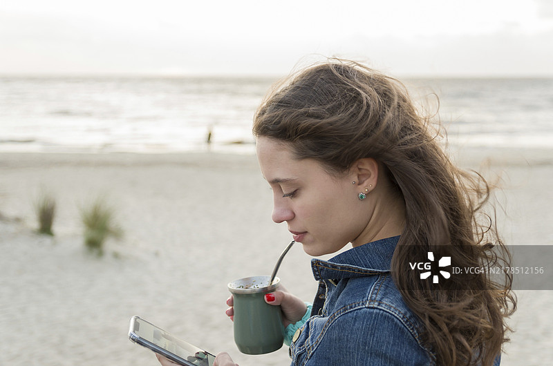 年轻女子在乌拉圭海滩上喝马黛茶图片素材