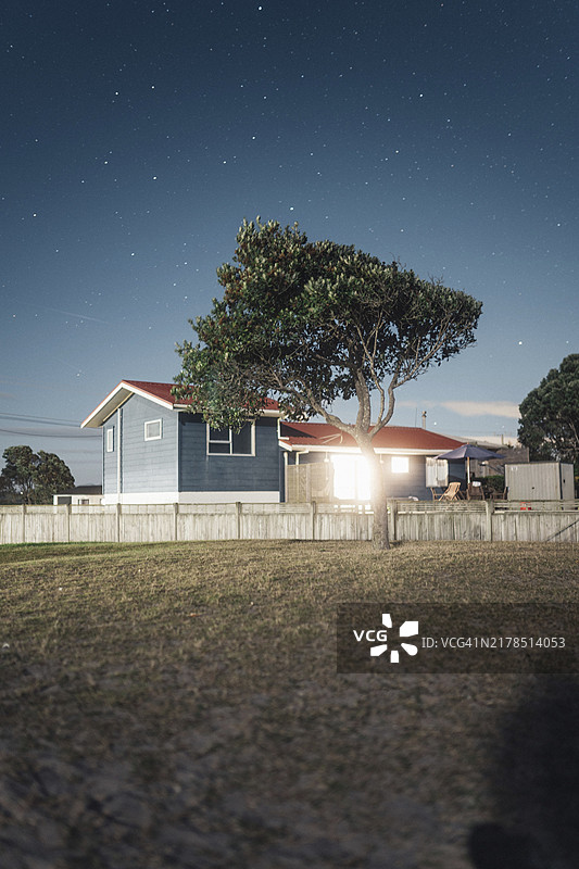 星空下，灯火通明的房子和门前的一棵树的夜景图片素材