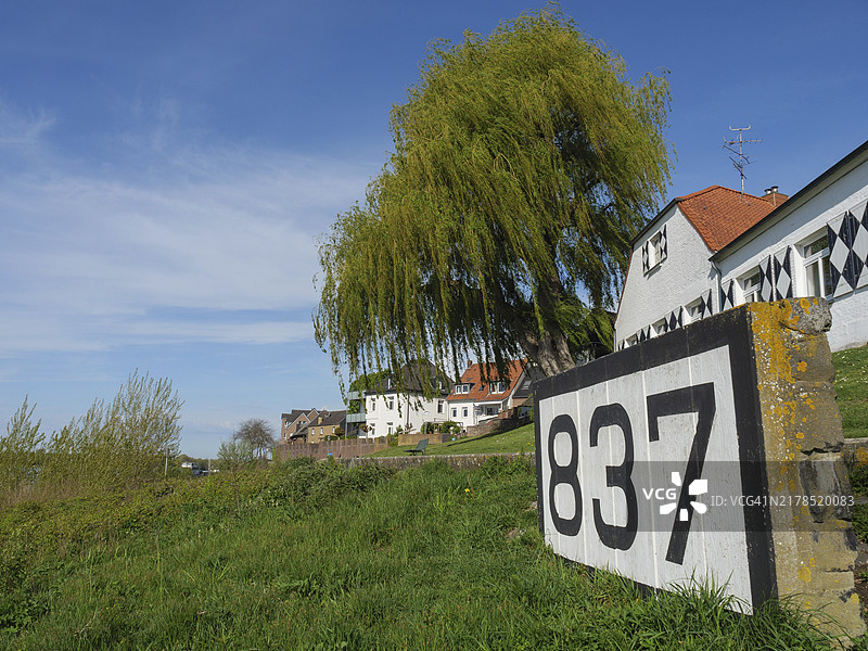 房子,绿色的草地上有一棵柳树和一个砖上的837号,德国里斯河畔河滨长廊上,有旧防御塔楼、房屋、灯笼和树木图片素材