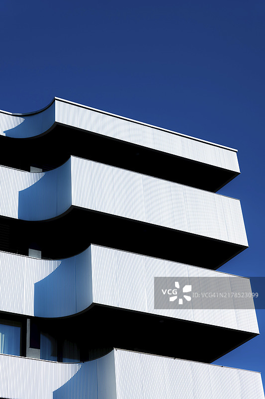 瑞士的现代混凝土设计建筑，带有金属阳台，背景是蔚蓝晴朗的天空图片素材