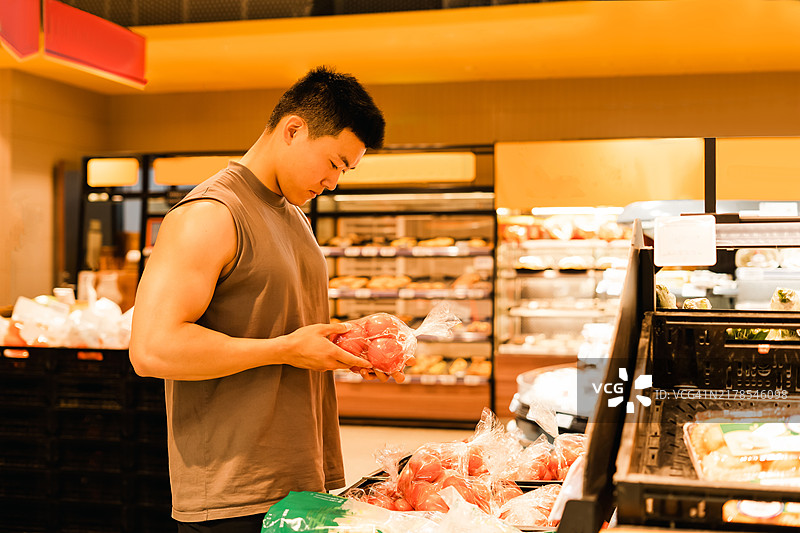 年轻的亚洲男子在超市购物图片素材