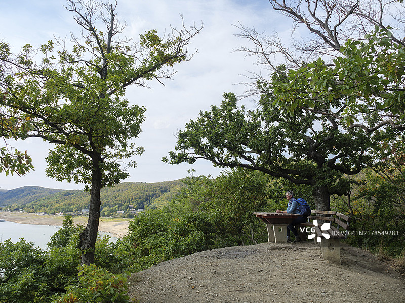 两人坐在树下长椅上欣赏德国黑森州瓦尔德克的美景图片素材