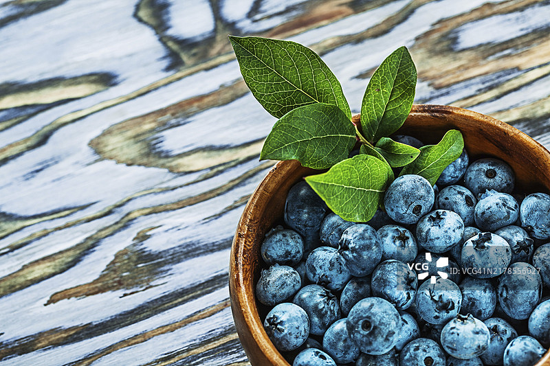 木碗木板上的蓝莓与绿叶图片素材