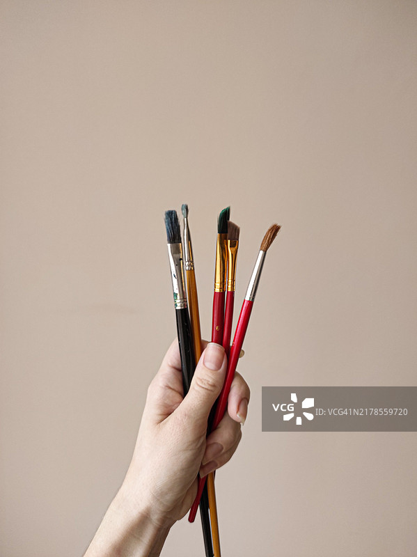 手持画笔，以墙为背景图片素材