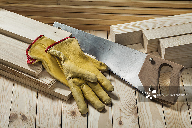 木质背景上的建筑手套和手锯图片素材