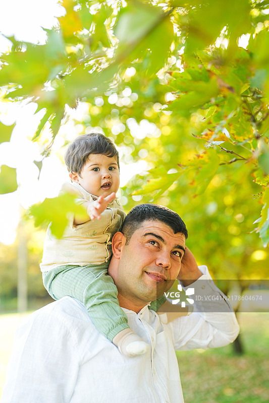 秋天公园里，男孩坐在父亲的肩膀上图片素材