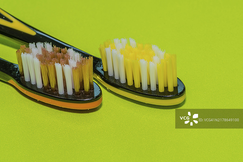 绿色背景下的橙色和黄色牙刷特写图片素材