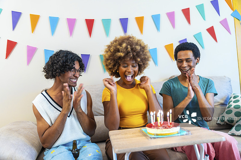 兴奋的非洲裔美国年轻女子在家与朋友庆祝生日图片素材