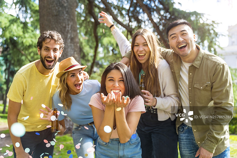 在公园里抛洒五彩纸屑的多民族狂欢群体，与朋友同乐图片素材