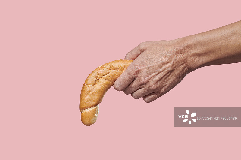 手持向下弯曲的长面包的男人图片素材