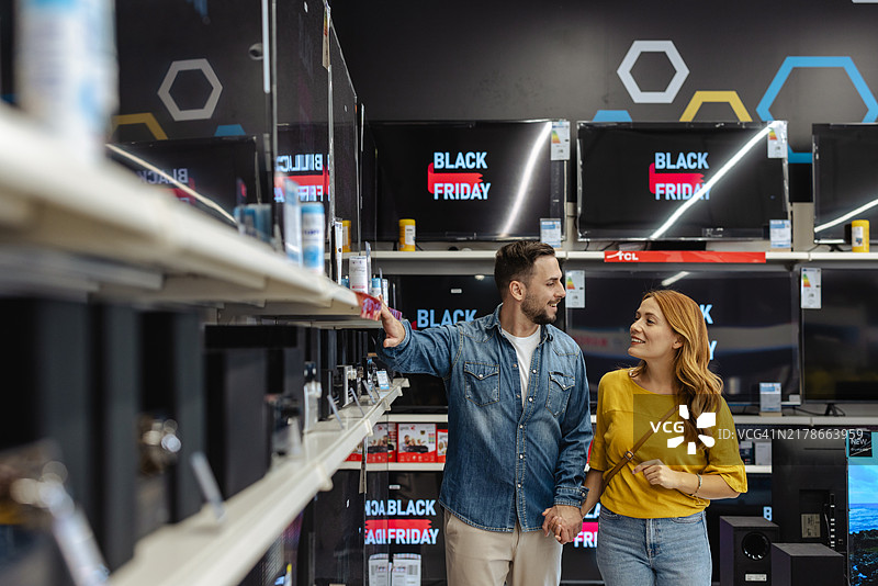 快乐的情侣在黑色星期五促销期间购买电子产品图片素材