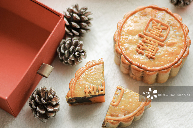 月饼切片，内馅显露，搭配松果和红色礼盒图片素材