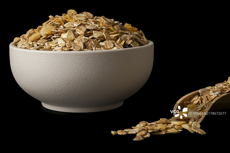 黑背景下带木勺的白色麦片碗特写：留有复制空间图片素材