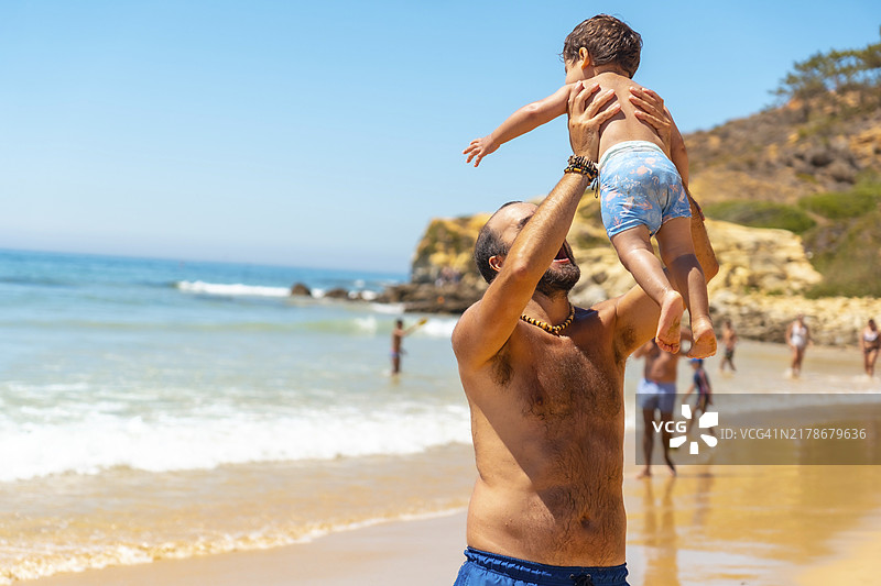 父亲在葡萄牙阿尔加维的巴兰科达斯贝尔哈鲁卡斯海滩和儿子玩沙子图片素材