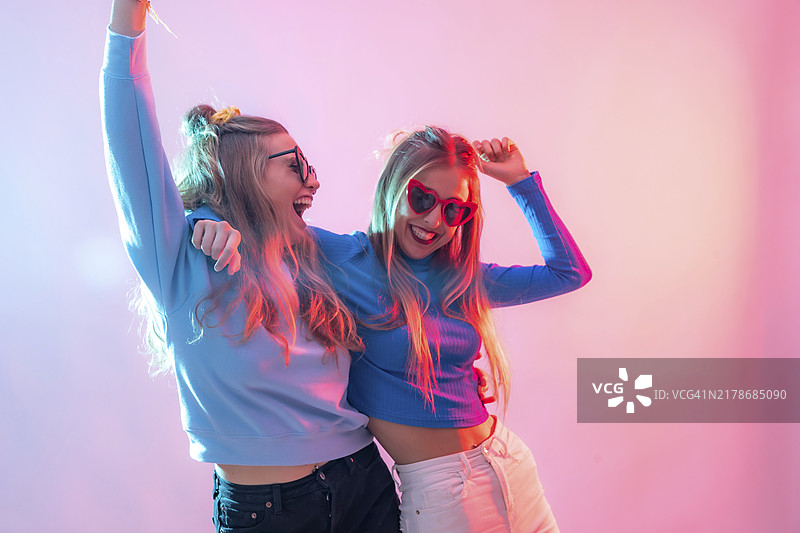 两个年轻的金发白人女性在迪斯科舞厅跳舞，微笑并享受派对乐趣图片素材