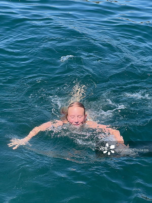 在阳光明媚的日子里在海里游泳的女孩图片素材