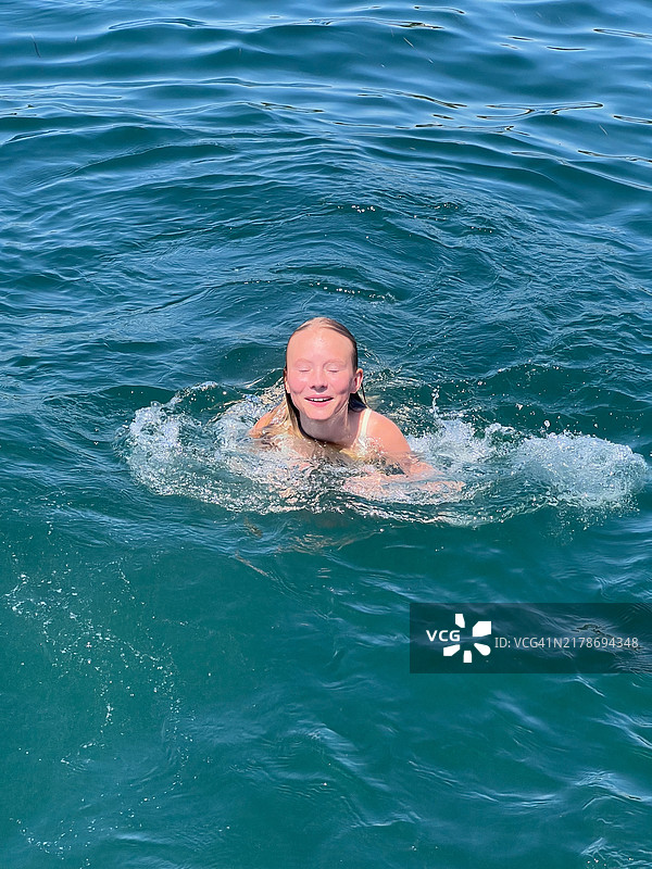 在阳光明媚的日子里在海里游泳的女孩图片素材