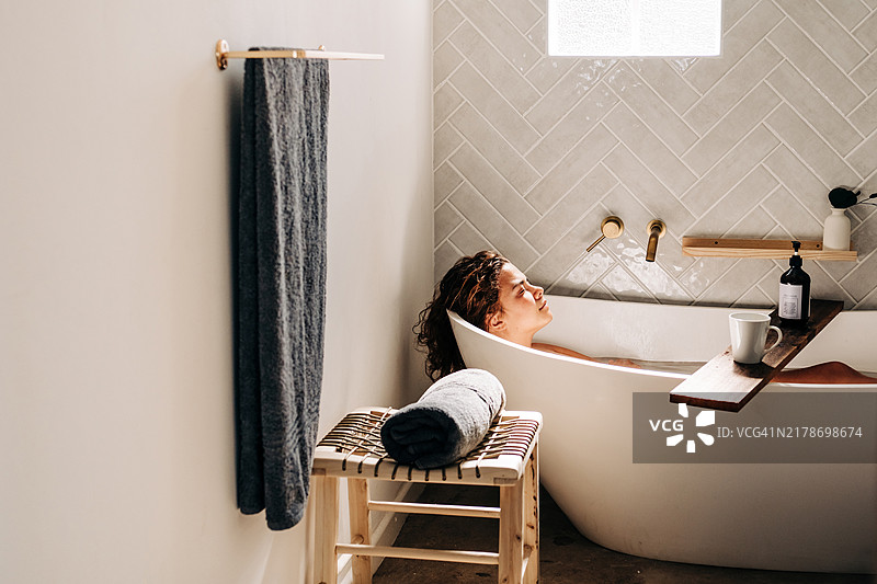 年轻女性在浴缸中放松。自我护理和心理健康概念。图片素材