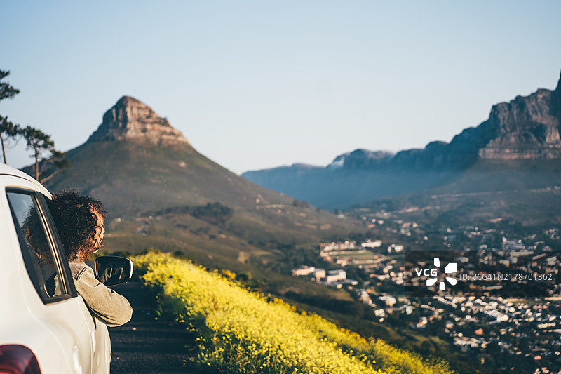男人们在公路旅行中欣赏风景。自信的男人站在他的车旁。图片素材