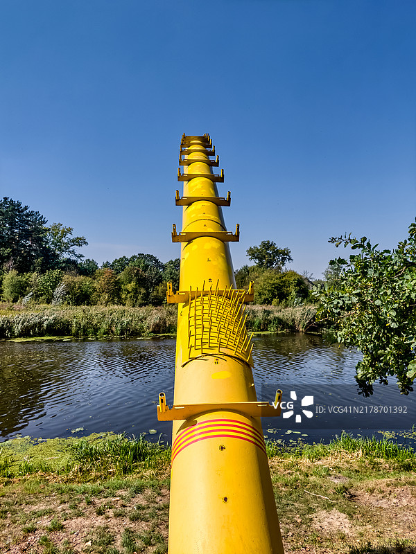 运河上方的明黄色工业管道图片素材