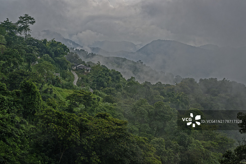 雾蒙蒙的山丘，一个小村庄坐落在阴天下的茂密树林中，南美洲哥伦比亚马格达莱纳圣玛尔塔山脉图片素材