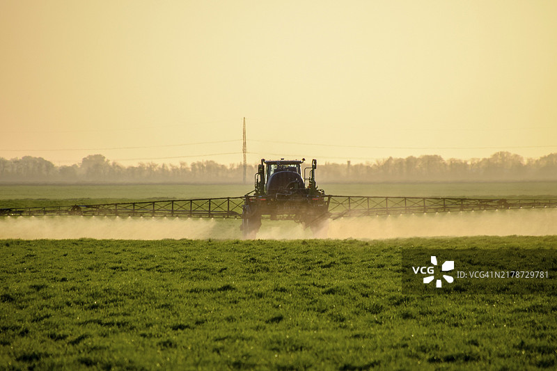 拖拉机在麦田上喷洒肥料图片素材