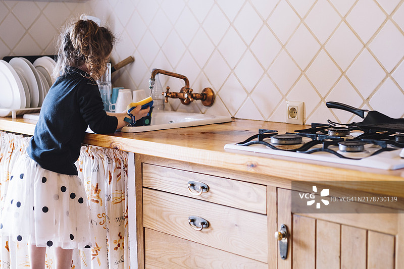 女孩在厨房水槽洗杯子图片素材