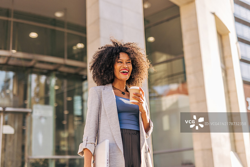 一位年轻快乐的黑人女商人在城市街道的现代建筑外图片素材