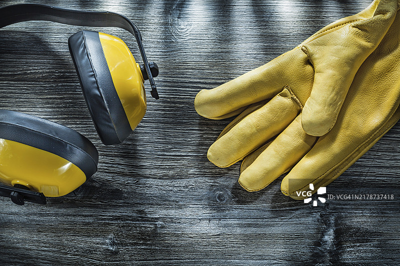 木板上的真皮安全手套和噪音防护耳罩图片素材