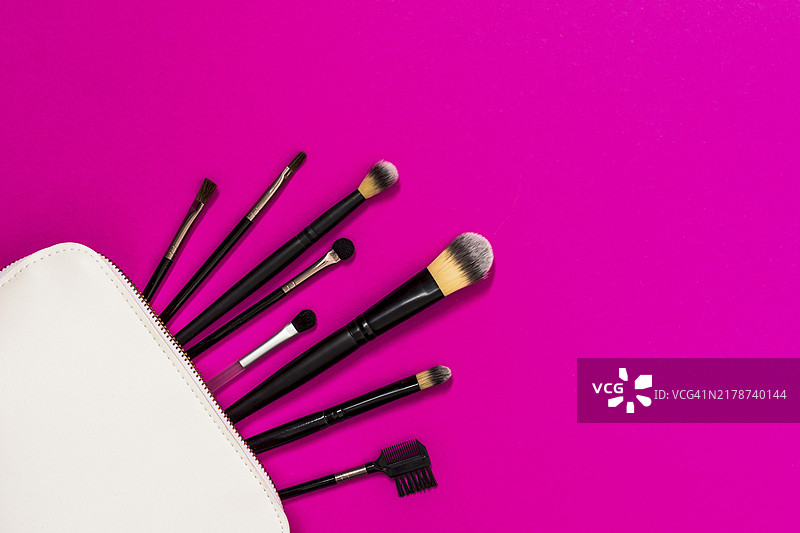 白色化妆包和粉色背景上的化妆刷图片素材
