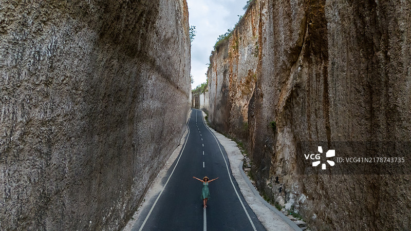 巴厘岛库塔的塔纳巴拉克海滩鸟瞰图：孤独的女人在石灰岩悬崖小路上行走图片素材
